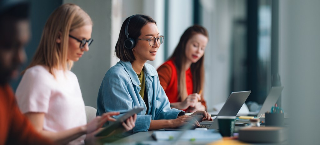 woman sitting at laptop between two other working people